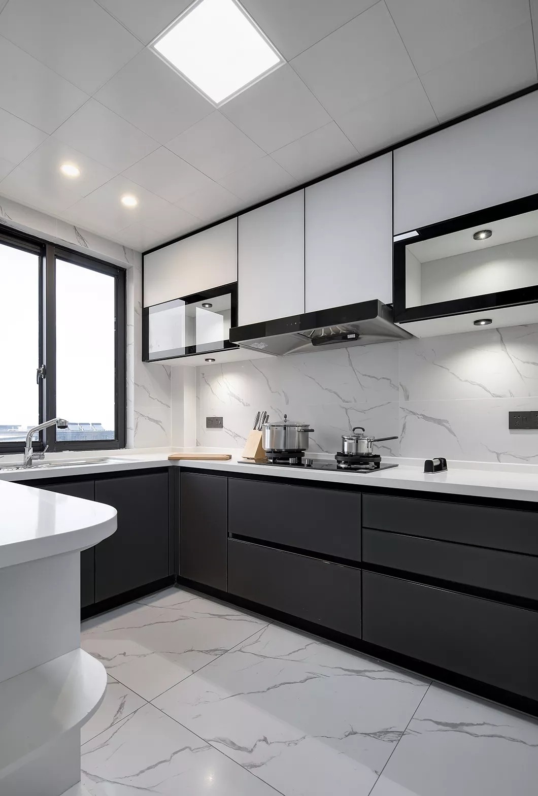 厨房在雅白的墙地面砖的空间基础,搭配深灰色的定制橱柜,还有白色的