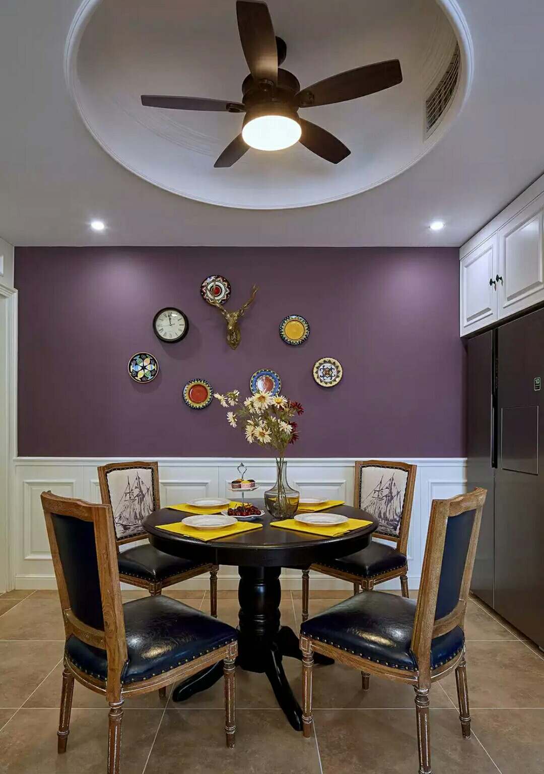 蓝色皮料与紫色背景墙的搭配，充满异域梦幻的格调，瓷砖与实木材质表面具有亚光的效果，使空间的质感变得细腻柔软，彩色挂盘与精巧的花呼应，点缀出日常饮食中的浪漫